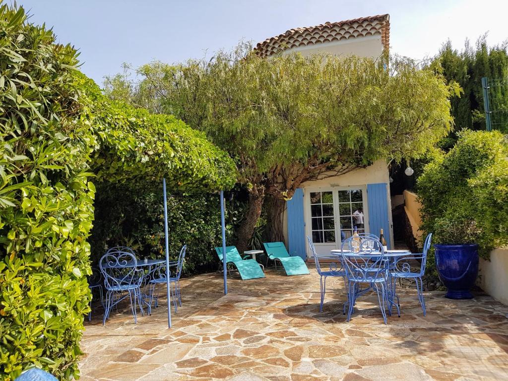 un patio avec des chaises, des tables et un arbre dans l'établissement Villa Adriandre, à Rayol-Canadel-sur-Mer