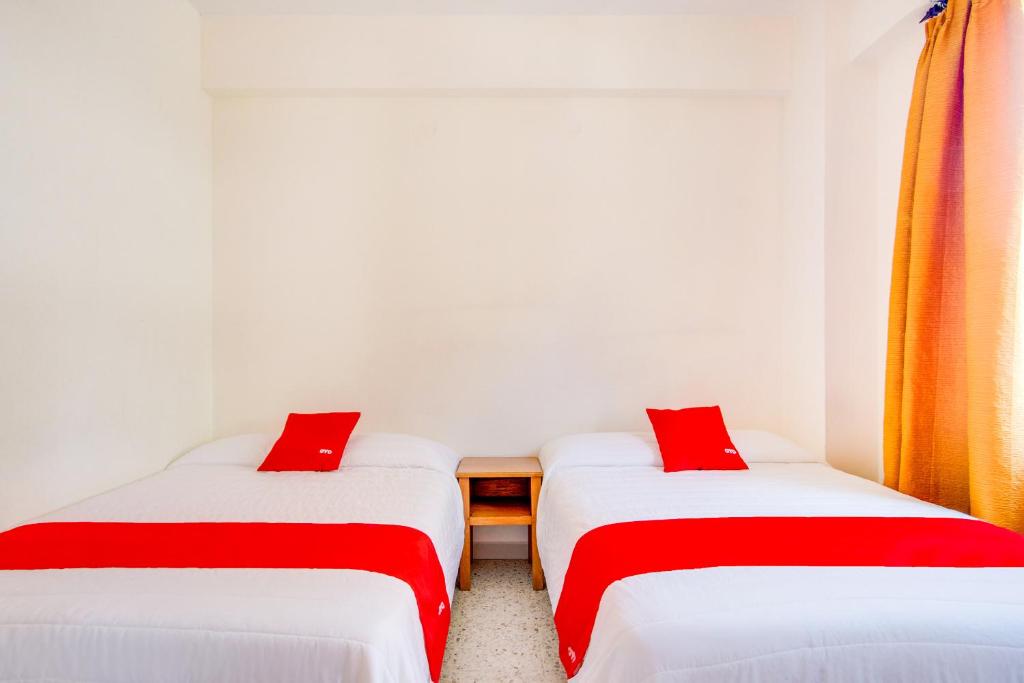 two twin beds in a room with red pillows at Hotel La Estancia in Colima