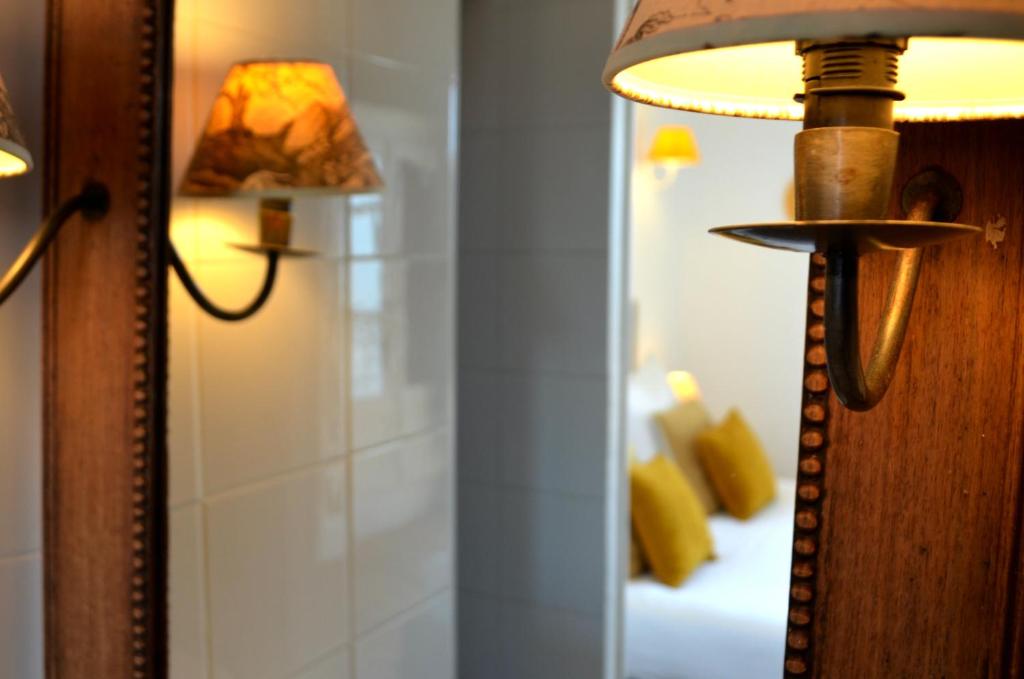 eine Lampe neben einem Spiegel in einem Zimmer in der Unterkunft Hôtel &amp; Espace Bien-être La Maison du Lierre in Biarritz