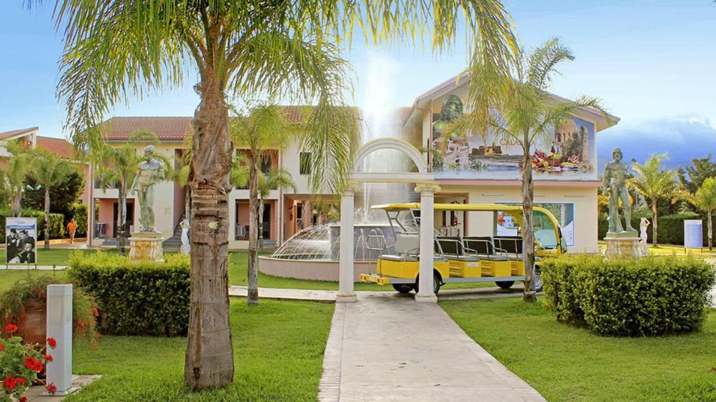una casa con un autobús amarillo estacionado frente a ella en Villaggio & Residence Club Aquilia, en Badolato