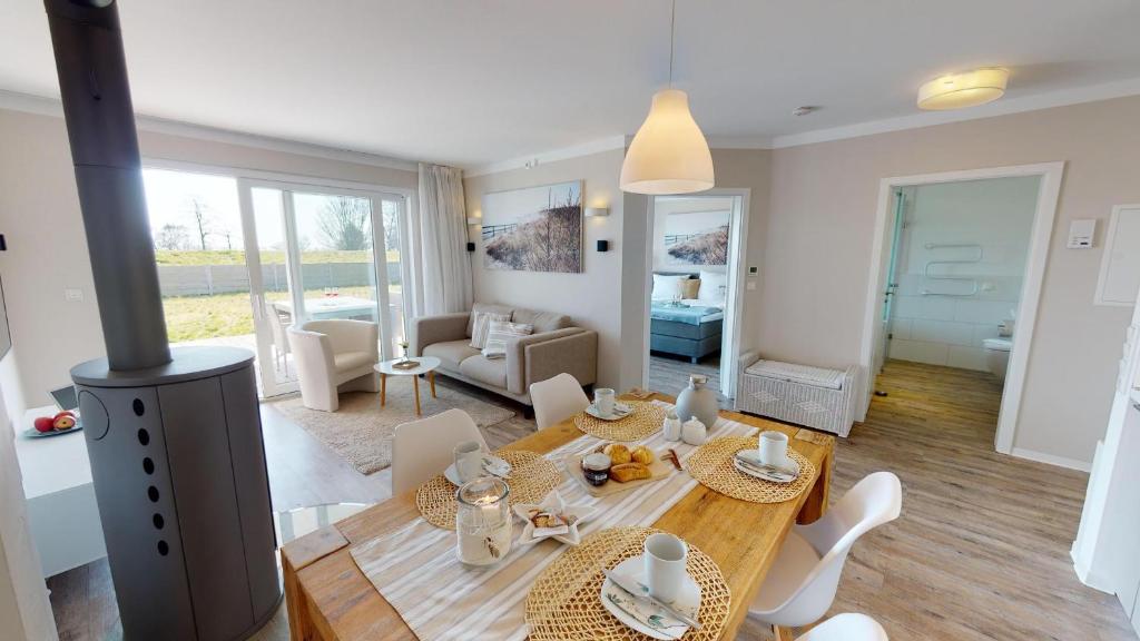 ein Wohnzimmer mit einem Tisch, Stühlen und einem Kamin in der Unterkunft Beach'n'Sea Wohnung 3 in Grömitz