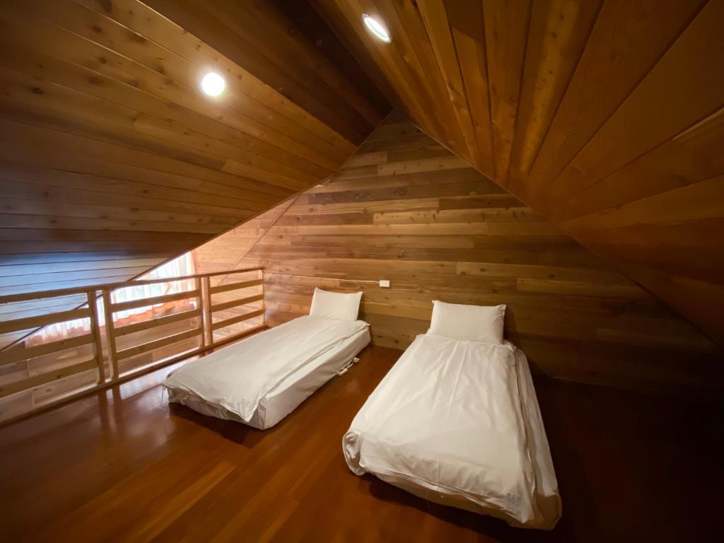 two beds in a room with wooden walls at Spring Ground Resort in Ren&#39;ai