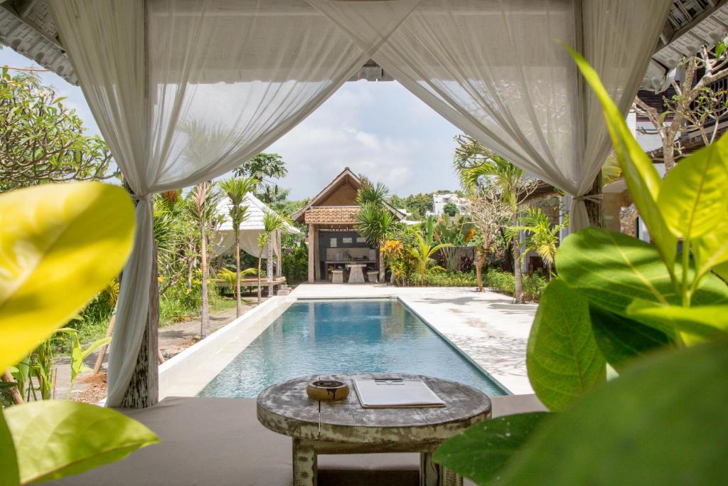 una piscina en una villa con una mesa delante en Mangga Wangga Living en Uluwatu