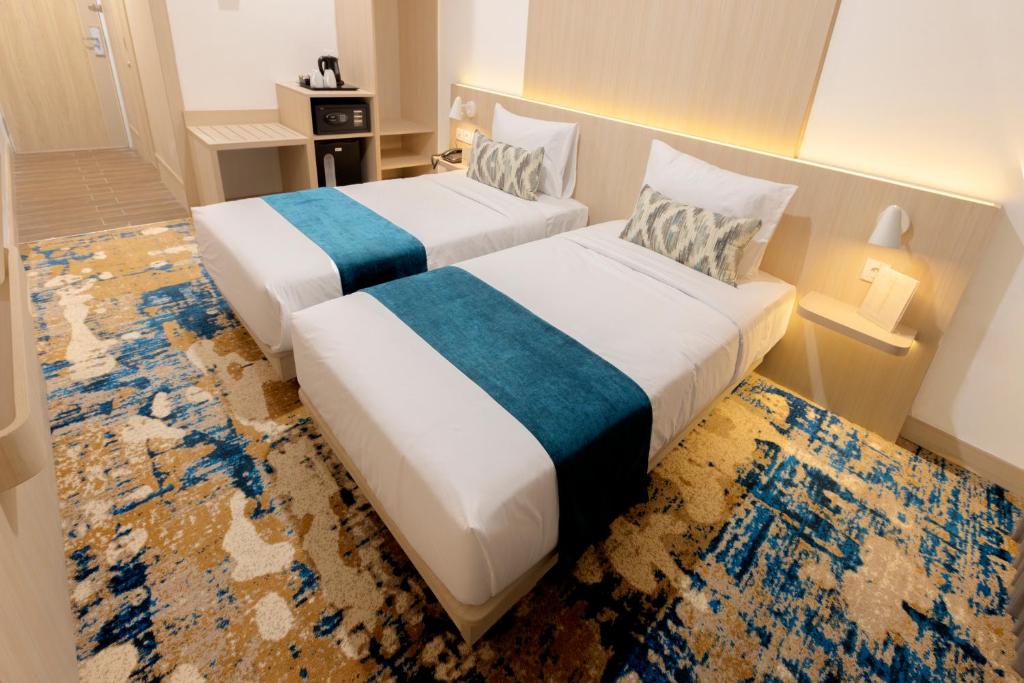 a hotel room with two beds in a room at Cordia Hotel Yogyakarta - Hotel Dalam Bandara in Glagah