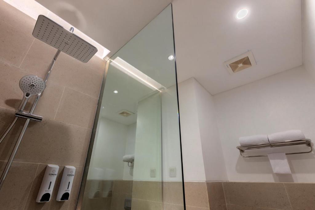 a shower with a glass door in a bathroom at Cordia Hotel Yogyakarta - Hotel Dalam Bandara in Glagah