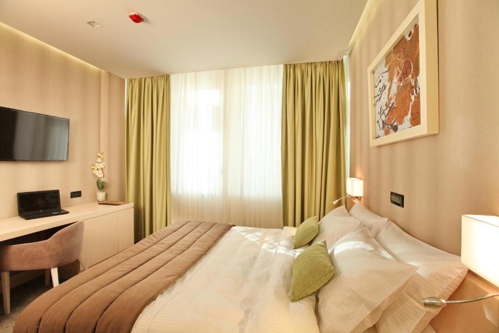 um quarto com uma cama, uma secretária e uma televisão em Hotel Argo em Belgrado