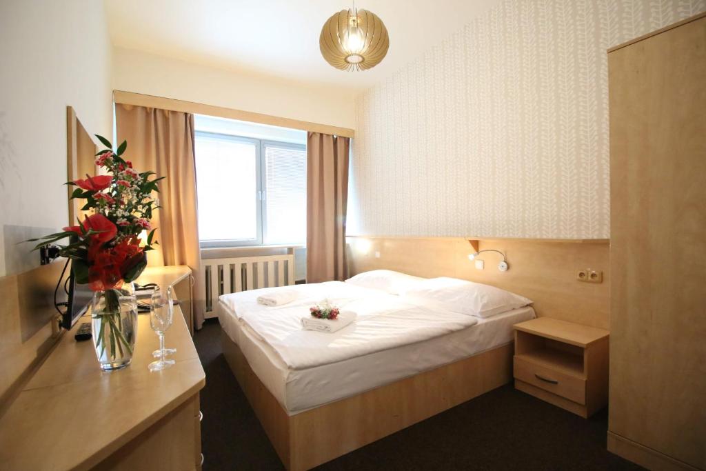 una habitación de hotel con una cama y un jarrón de flores en Abitohotel en Praga