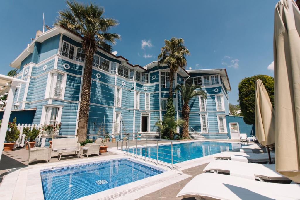 a large blue building with a swimming pool and palm trees at Pamukkale Melrose Viewpoint Suites in Pamukkale