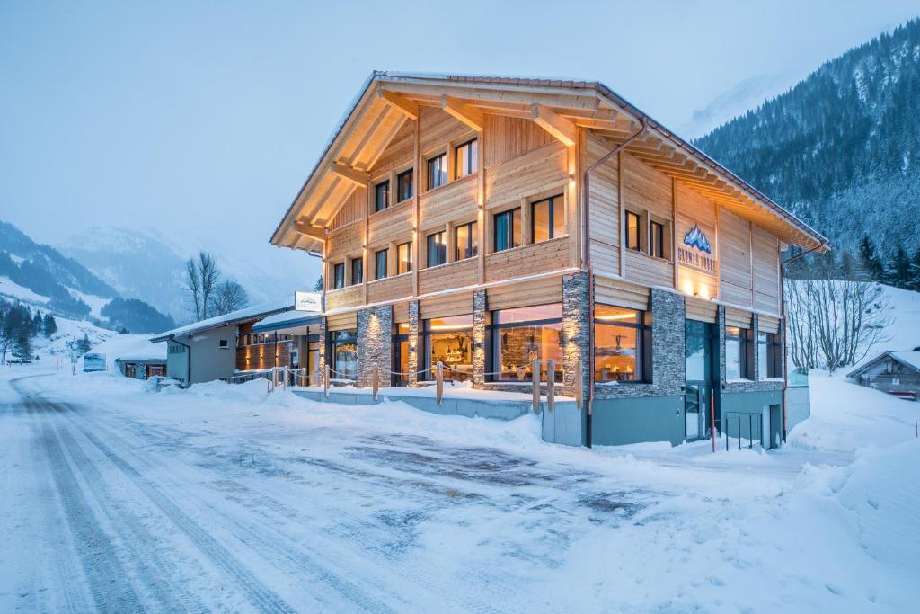 un gran edificio de madera en una carretera cubierta de nieve en Gadmer Lodge - dein Zuhause in den Bergen en Gadmen