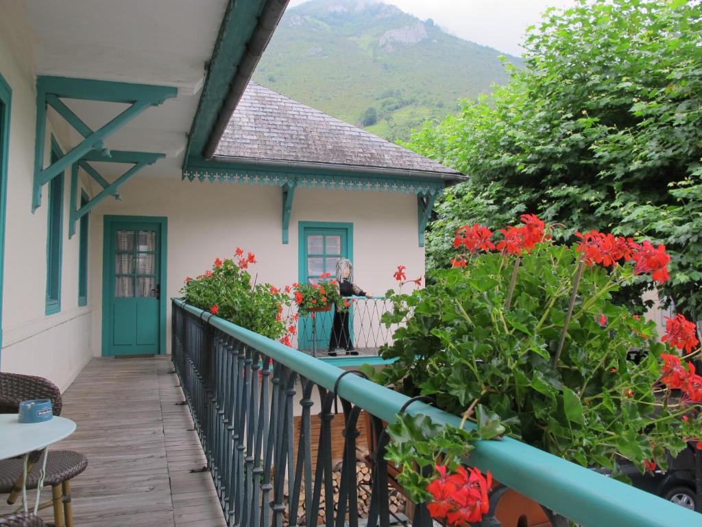 uma mulher de pé na varanda de uma casa com flores em La Cazalère em Campan