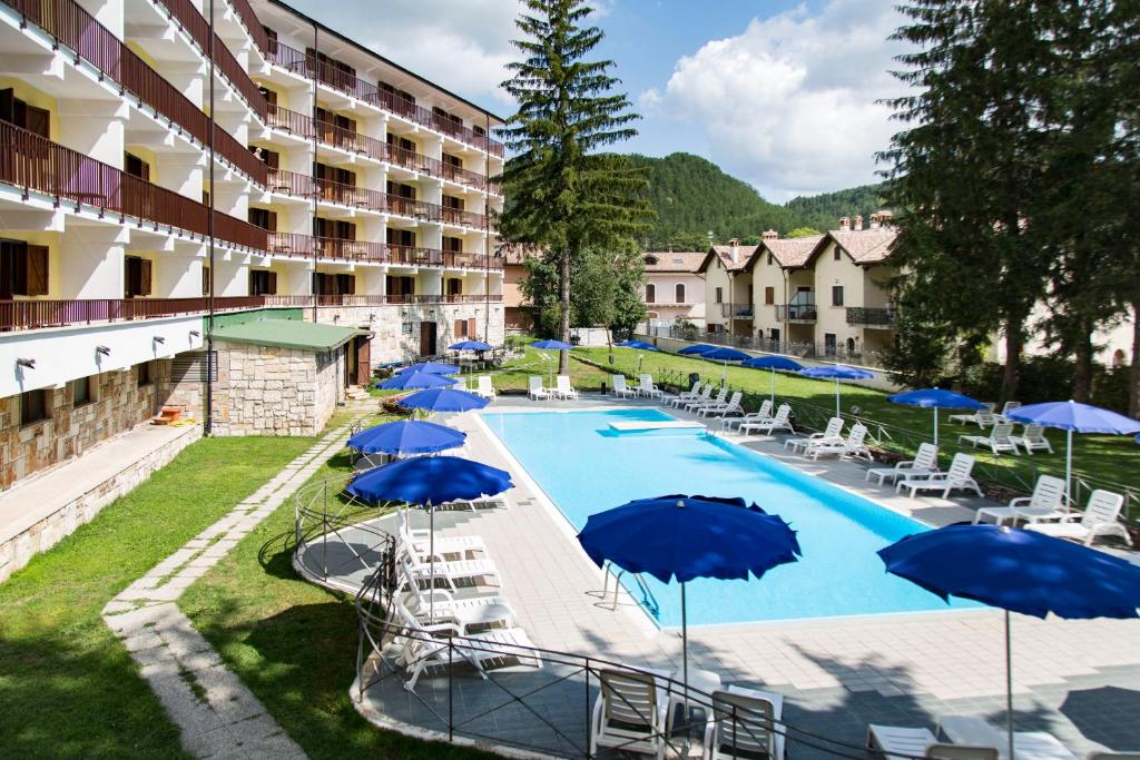 une piscine avec des parasols et des chaises et un hôtel dans l'établissement Grand Hotel del Parco, à Pescasseroli