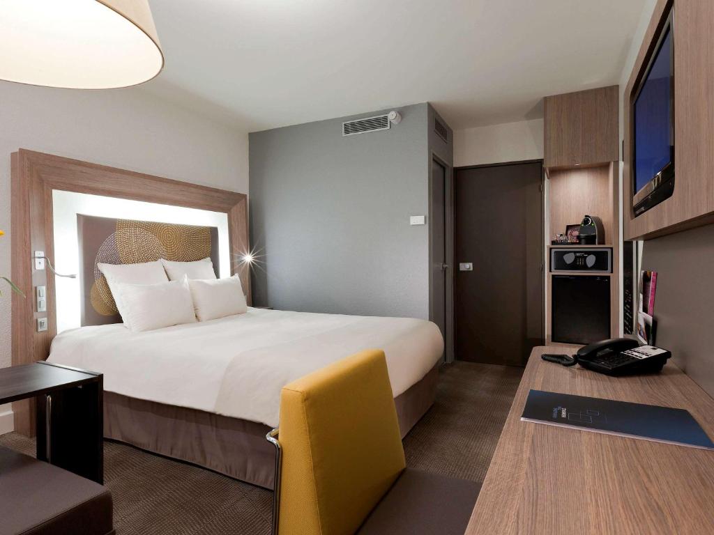 a hotel room with a large bed and a desk at Novotel Paris La Defense Esplanade in Courbevoie