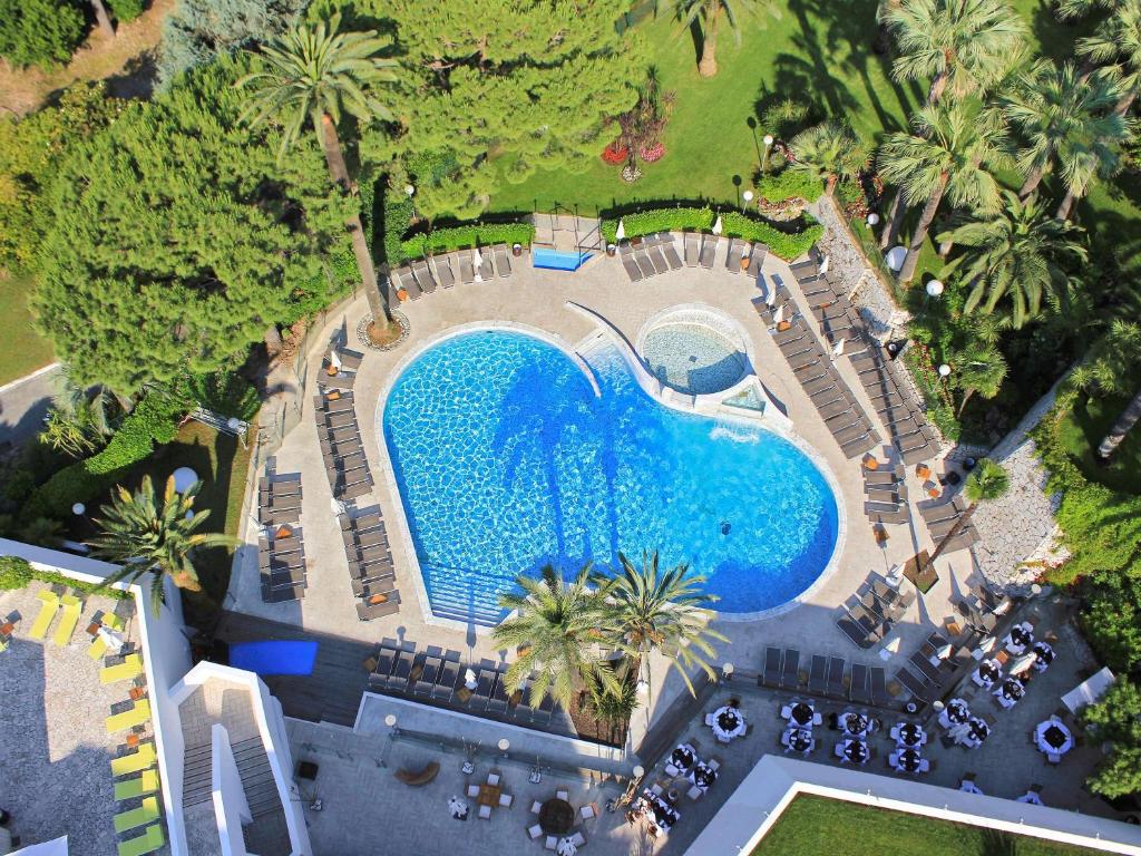 an overhead view of a pool with chairs and palm trees at Hotel Cannes Montfleury in Cannes