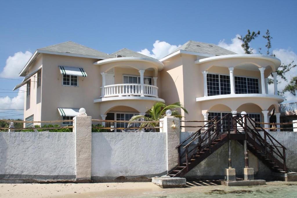 a white house with a staircase in front of it at Triplets on the Bay in Montego Bay