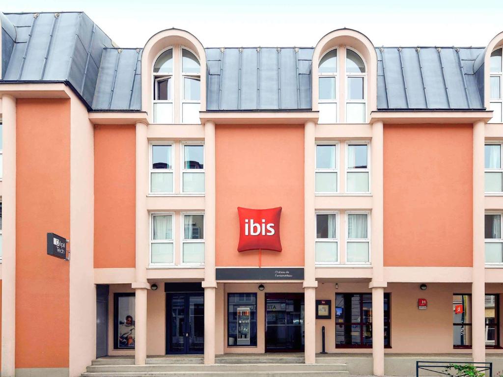 un grande edificio arancione con un cartello con le zie di ibis Château de Fontainebleau a Fontainebleau