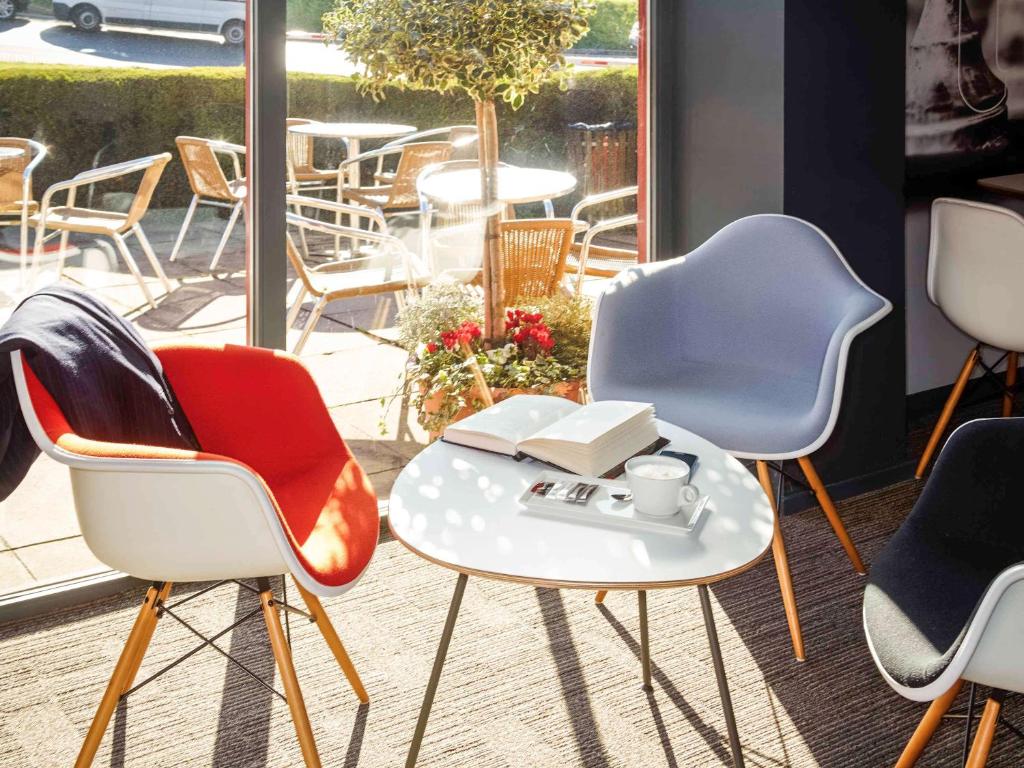 a group of chairs and a table with a cup of coffee at ibis London Luton Airport in Luton