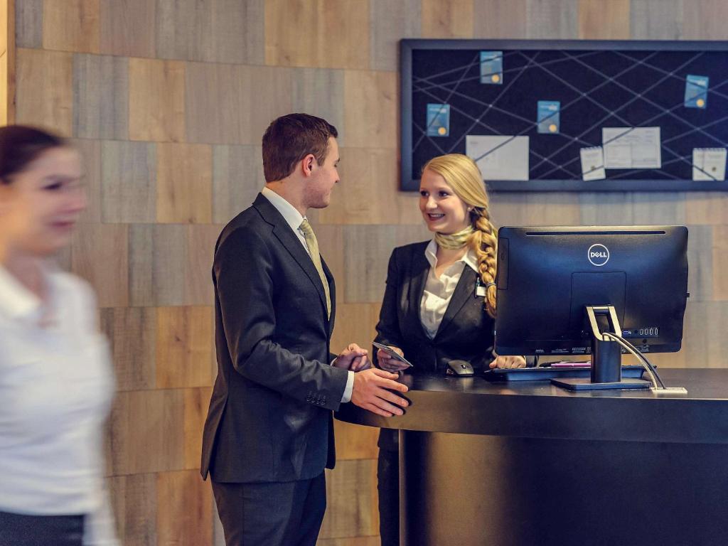 a man and a woman standing in front of a computer at Mercure München City Center in Munich