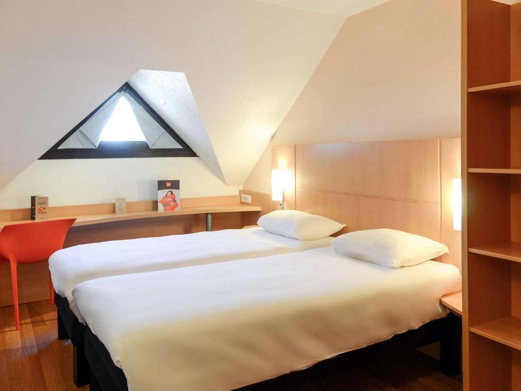 a hotel room with two beds and a window at Hôtel Ibis Nevers in Nevers