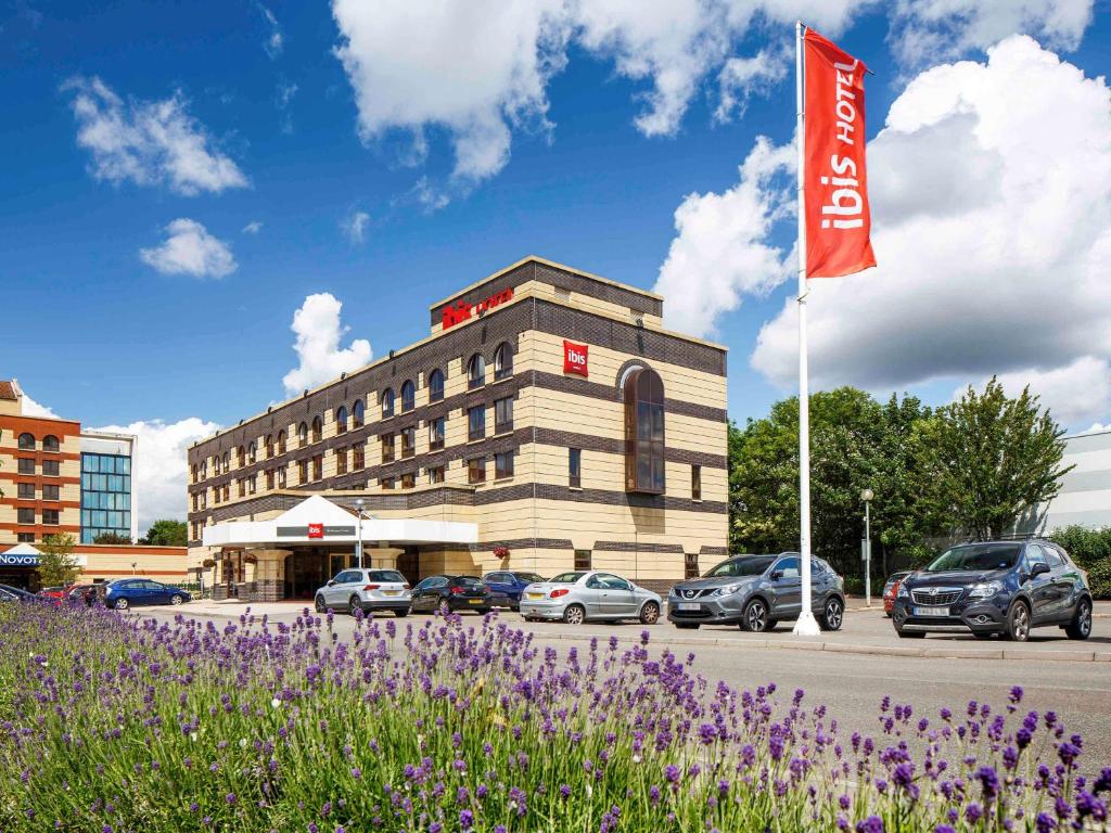 a building with cars parked in a parking lot with a flag at ibis Southampton in Southampton