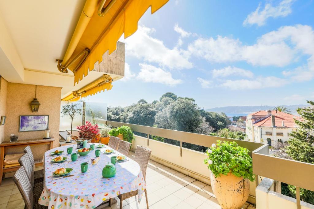 einen Balkon mit einem Tisch und Stühlen sowie Aussicht in der Unterkunft LE CHATEAU DE LA PINEDE AP4198 by Riviera Holiday Homes in Juan-les-Pins