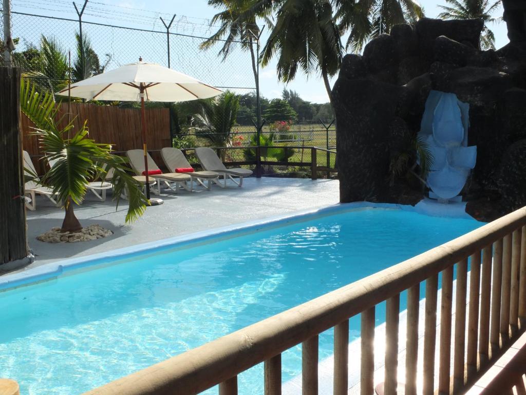 a swimming pool on a fence with an umbrella at Eden Villa in Belle Mare