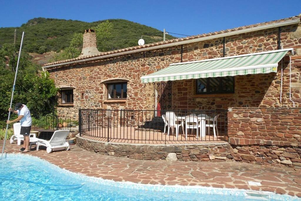 un homme debout devant une maison avec piscine dans l'établissement La Bergerie, with private pool and garden, à Lodève