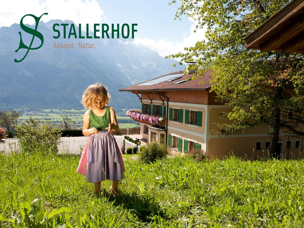 Ein kleines Mädchen steht im Gras vor einem Haus in der Unterkunft Stallerhof in Golling an der Salzach