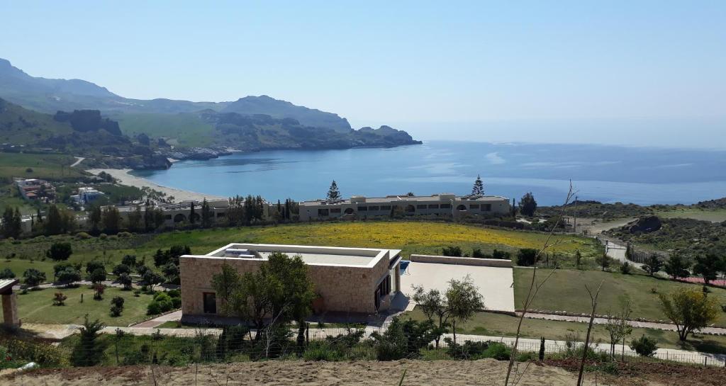 a building on a hill next to a body of water at Zefyros Studios in Damnoni