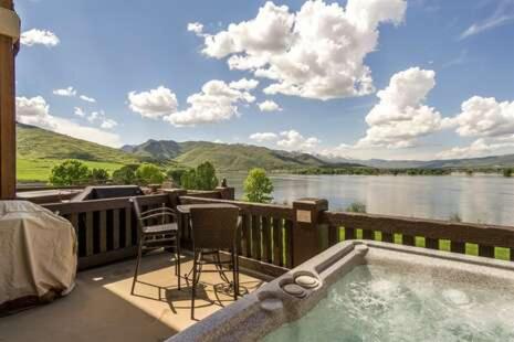 a hot tub on a deck with a view of a lake at 2 Bedroom Snowbasin Vacation Rental - Huntsville, Utah Lodging Options LS63 in Huntsville