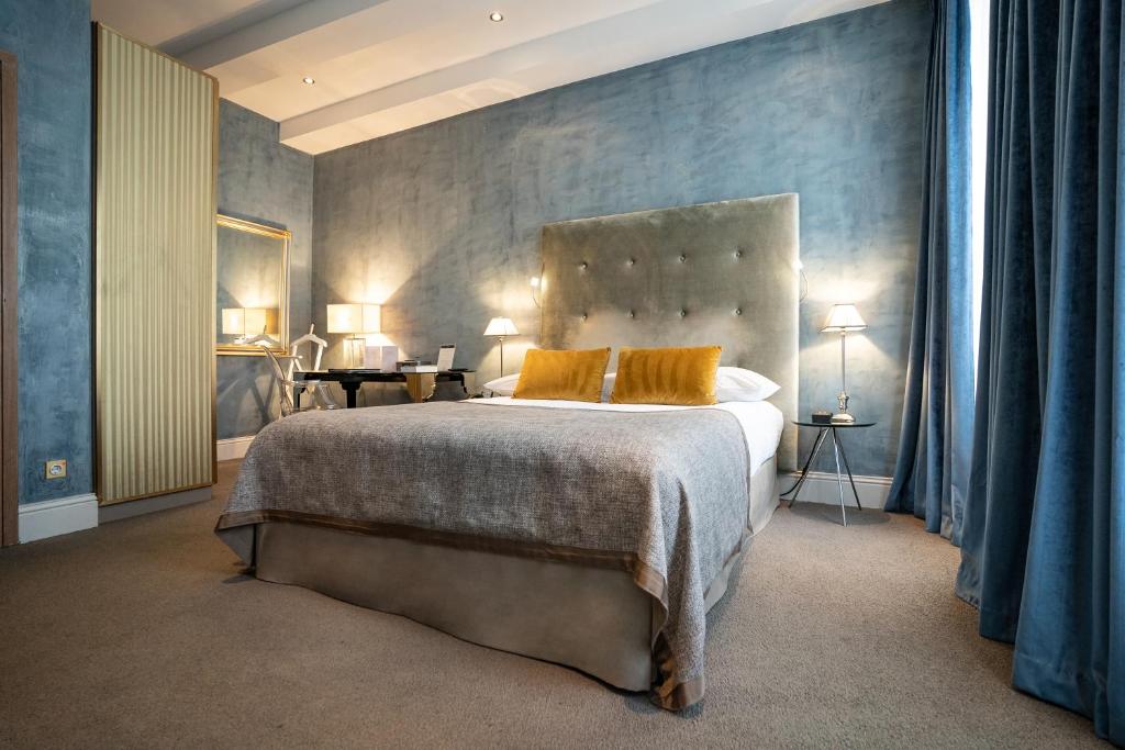 a bedroom with a large bed with yellow pillows at Hotel Le Place d'Armes - Relais & Châteaux in Luxembourg