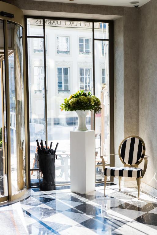 a vase with flowers in a room with a window at Hotel Le Place d'Armes - Relais & Châteaux in Luxembourg