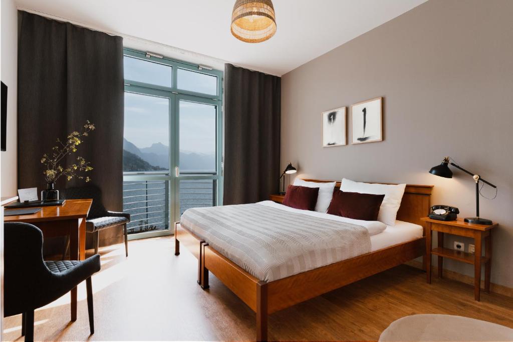 a bedroom with a bed and a desk and a window at Hotel Esplanade in Gmunden