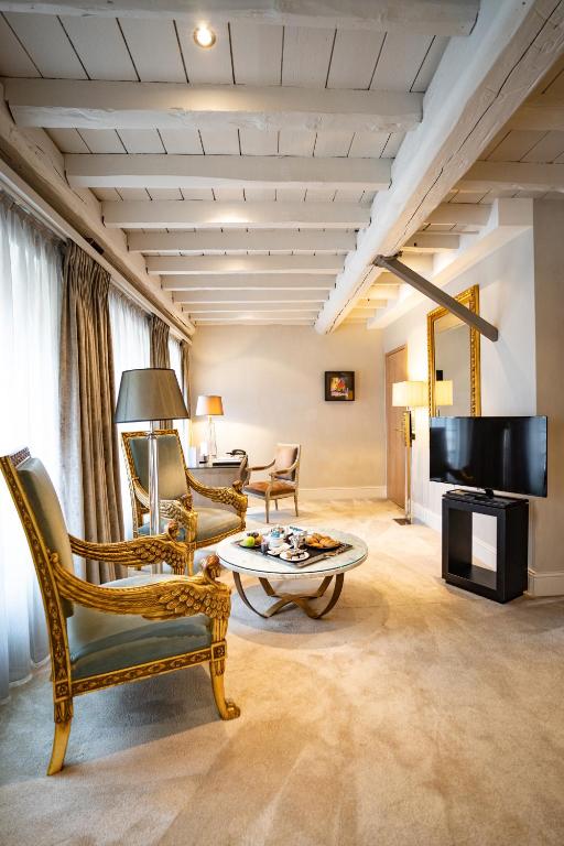 a living room with chairs and a table and a tv at Hotel Le Place d'Armes - Relais & Châteaux in Luxembourg