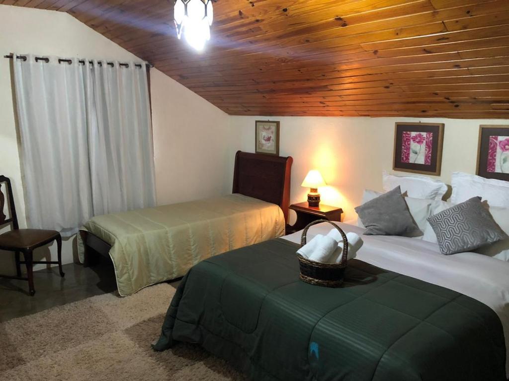 a bedroom with two beds and a wooden ceiling at Hospedagem Platô in Monte Verde