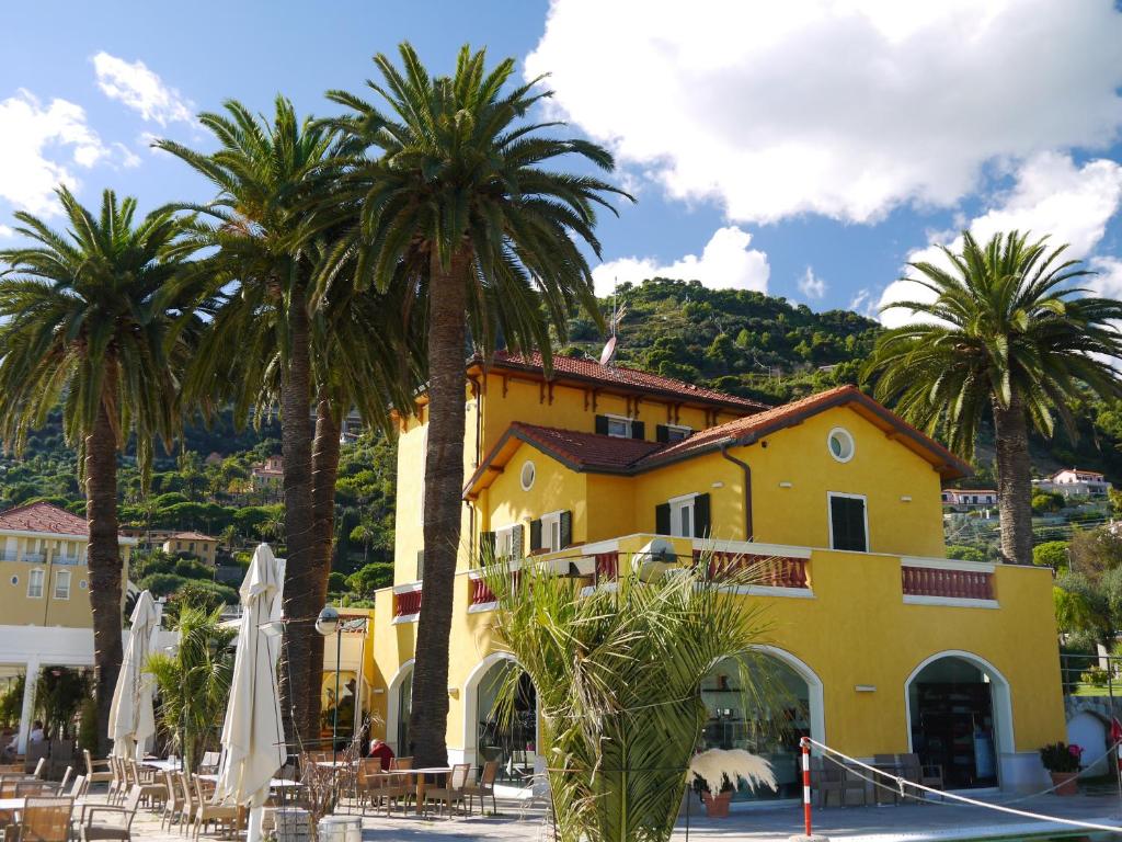 un edificio amarillo con palmeras delante en Villa Eva Beach, en Ventimiglia