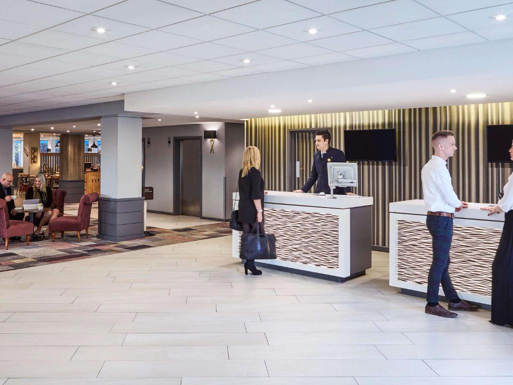 a group of people standing at a counter in a lobby at Novotel Wolverhampton City Centre in Wolverhampton