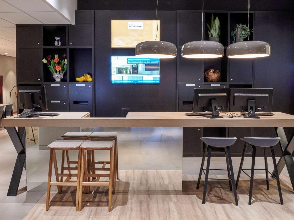 a kitchen with a large table and stools at Mercure Hotel Tilburg Centrum in Tilburg