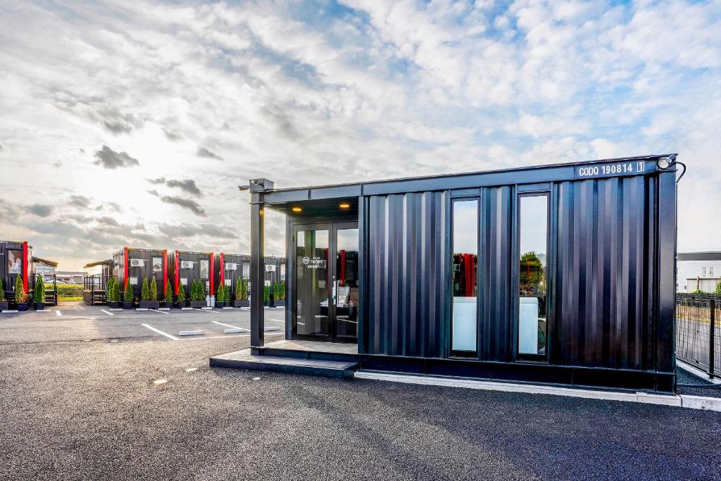 un edificio con puertas de cristal en un aparcamiento en HOTEL R9 The Yard Ashikagafukutomi, en Ashikaga