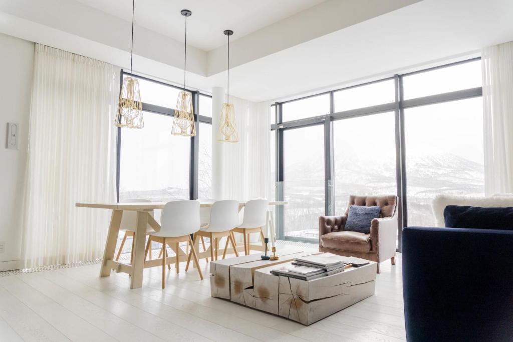 een witte woonkamer met een tafel en stoelen bij Loft Niseko in Niseko