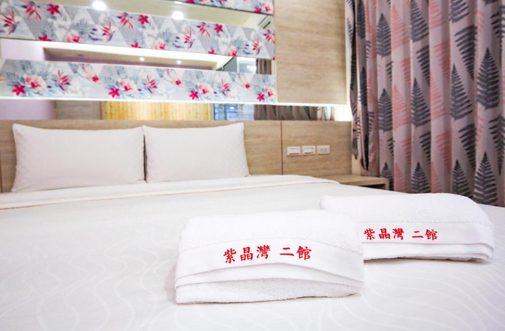 1 dormitorio con 2 camas y toallas rojas y blancas en Amethyst Bay Theme HomeStay II, en Magong