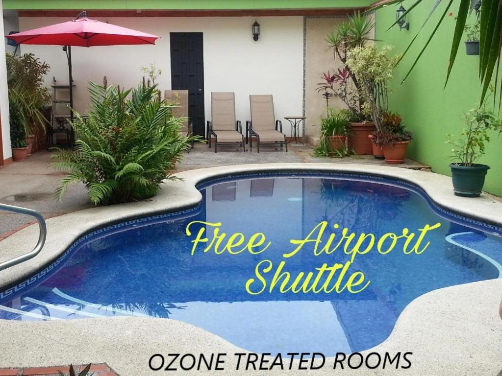 una piscina con un cartel que lee el servicio de enlace con el aeropuerto en Hotel La Guaria Inn & Suites, en Alajuela