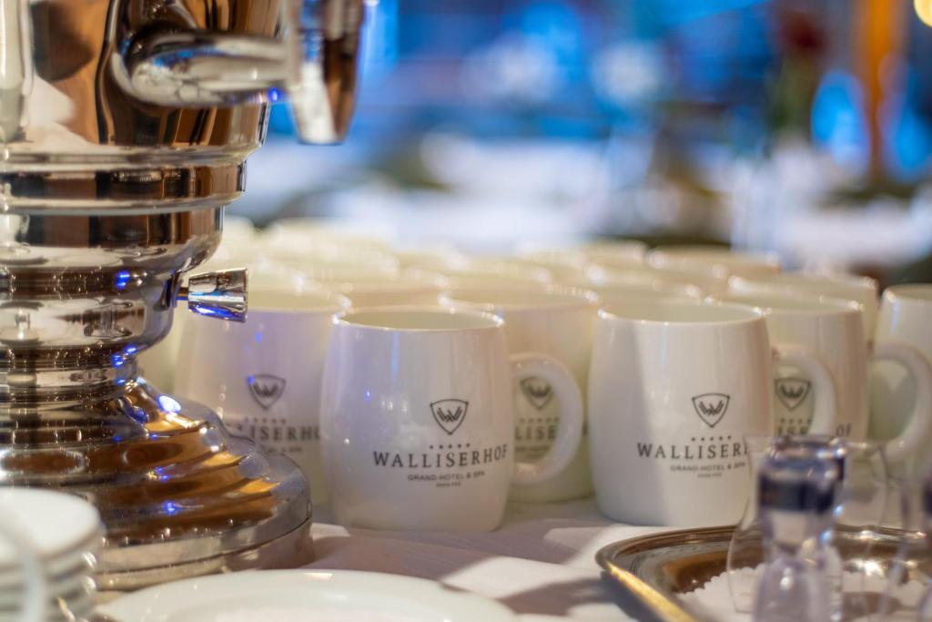a row of coffee cups sitting on a counter with a coffee machine at Walliserhof Grand-Hotel & Spa Relais & Châteaux in Saas-Fee