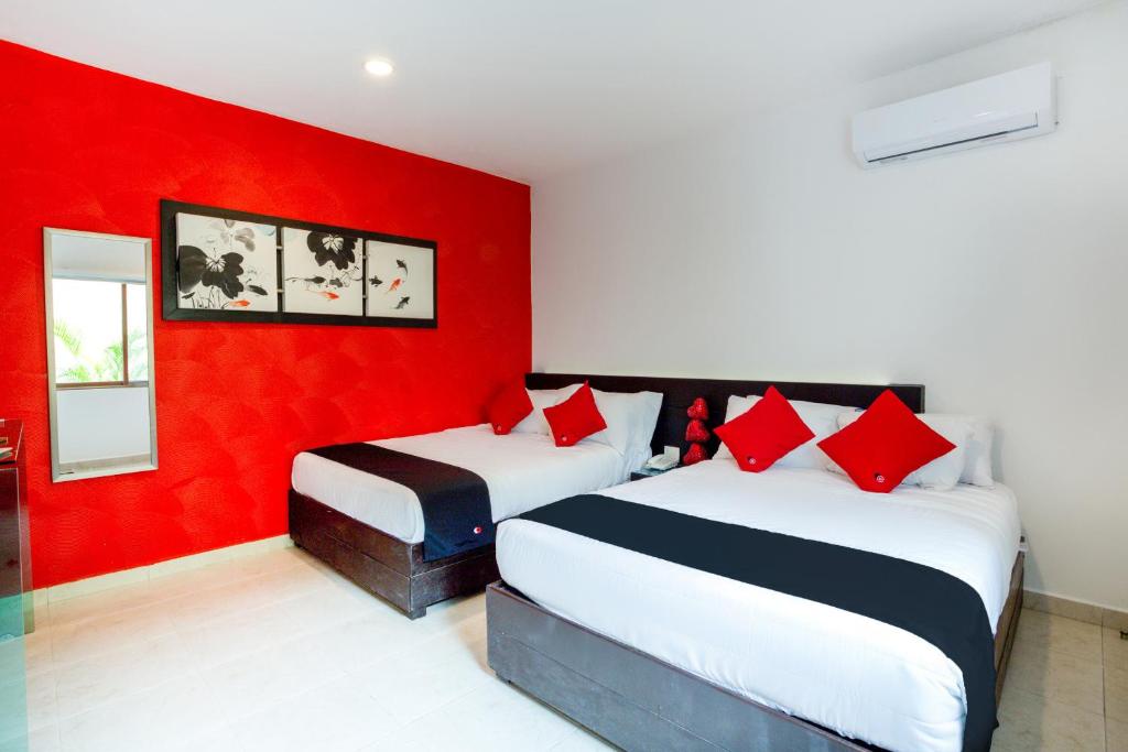 2 camas en una habitación con una pared roja en Quinta Santa Anita, en Playa del Carmen