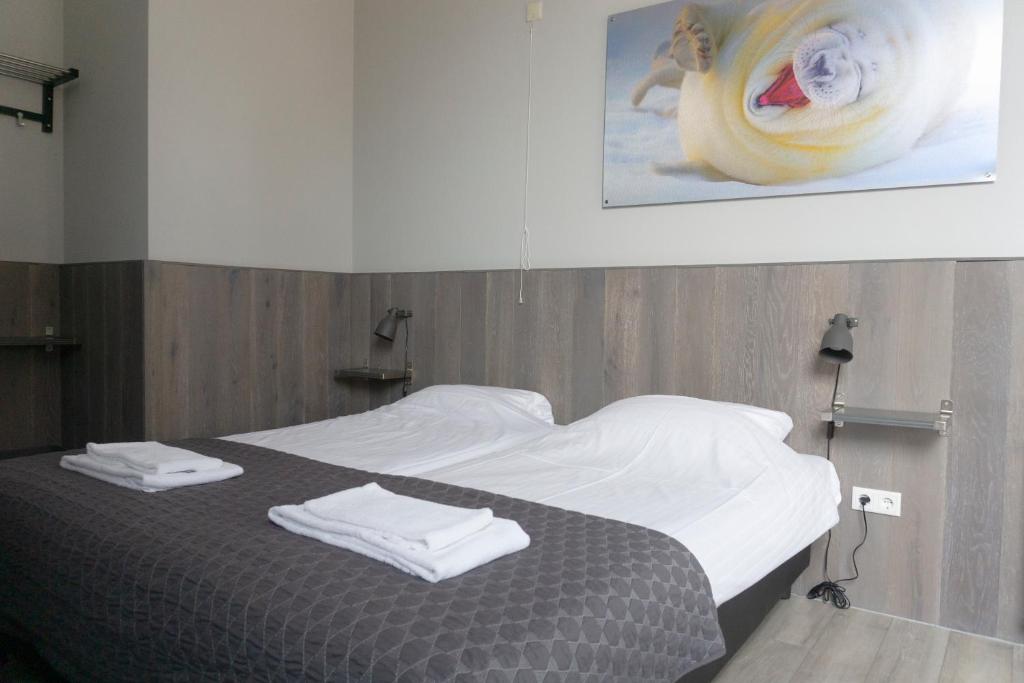 een slaapkamer met een bed met handdoeken erop bij Hotel Waddengenot in Pieterburen