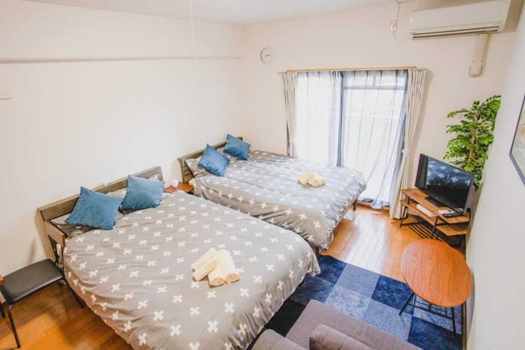 two beds in a room with blue pillows at KYOBASHI BASE in Osaka