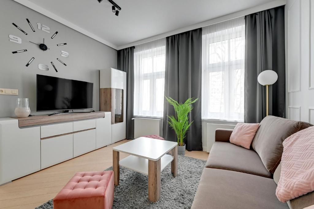 salon z kanapą i zegarem na ścianie w obiekcie Royal Rose - Premium Beach Apartment w mieście Sopot
