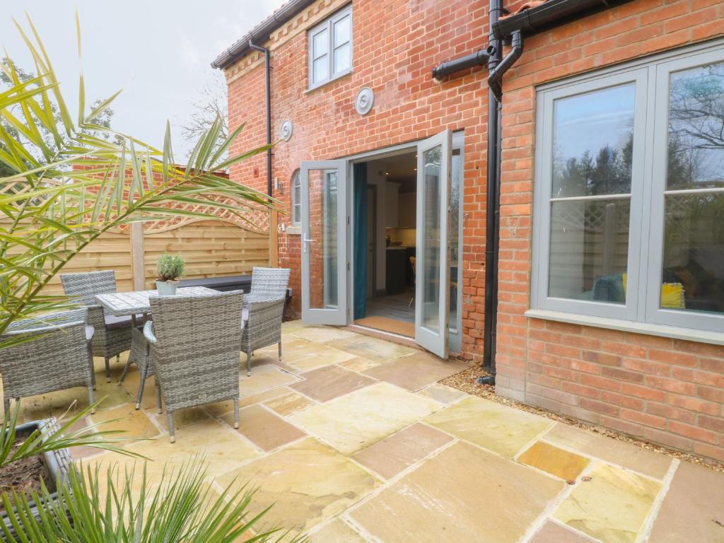 een patio met een tafel en stoelen voor een gebouw bij The Old Rectory Coach House in Norwich