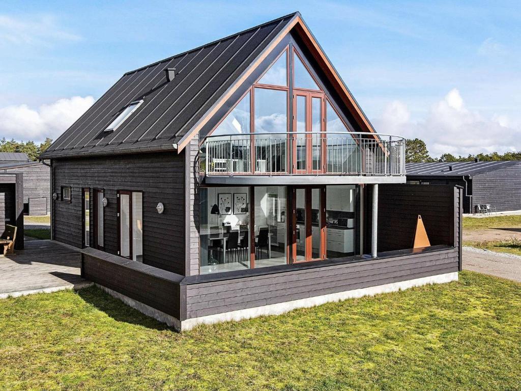 a black house with a deck on the grass at 6 person holiday home in R m in Sønderby