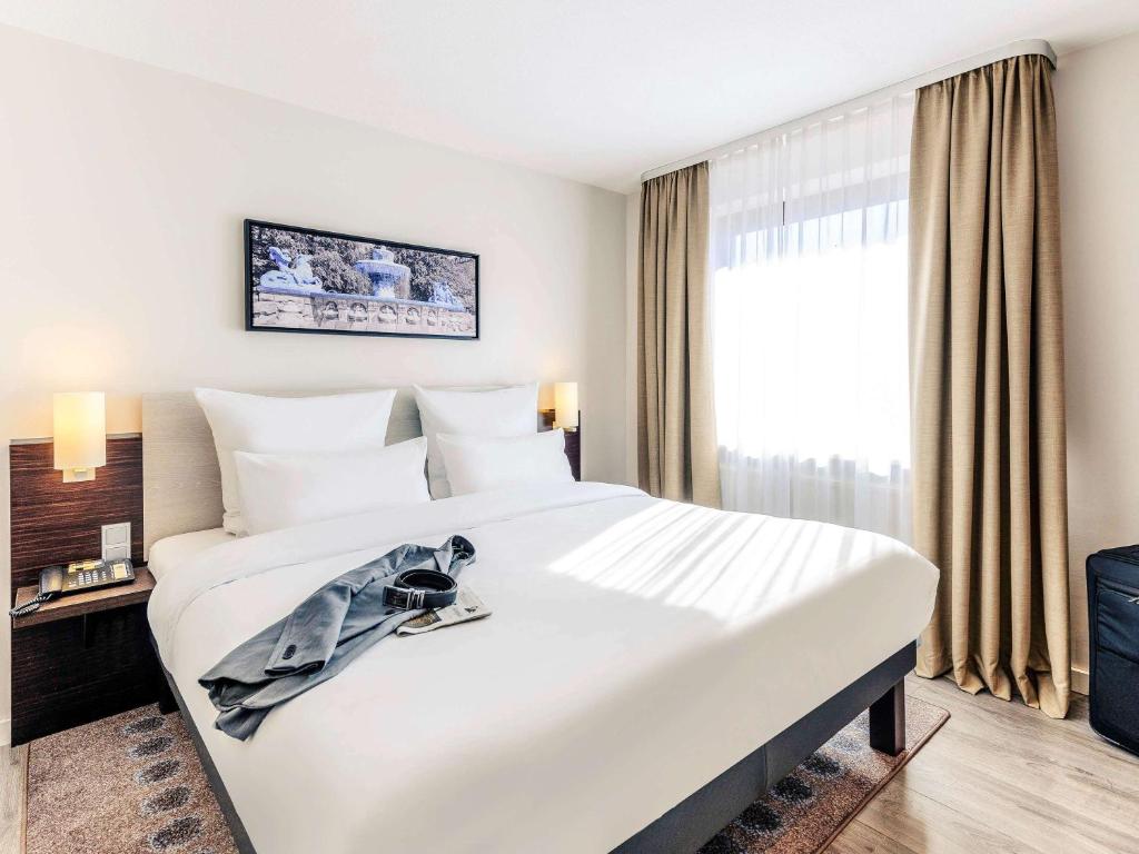 1 cama blanca grande en una habitación de hotel con ventana en Mercure Hotel München Süd Messe, en Múnich