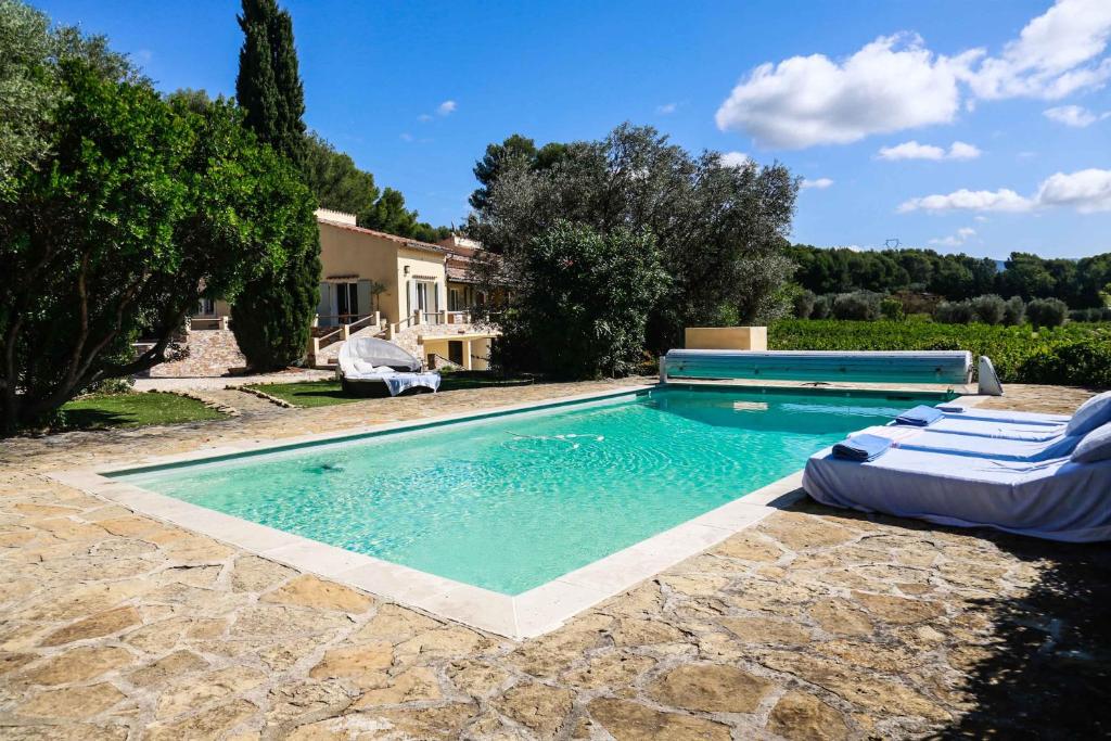 - une piscine avec 2 chaises longues et une maison dans l'établissement Luxueux Mas provencal immérgé dans la nature, au Castellet